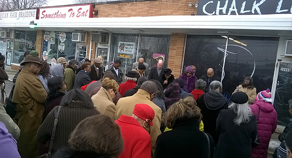 Aldersgate UMC members pray in front of Chalk Lines barber shop