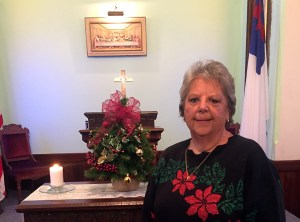 Carolyn Thompson holding Christmas tree in from of alter