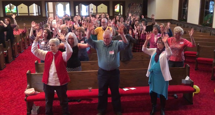 Attendees standing, hands up in the air