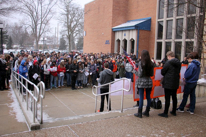 massive group of students bow heads for moment of siklence