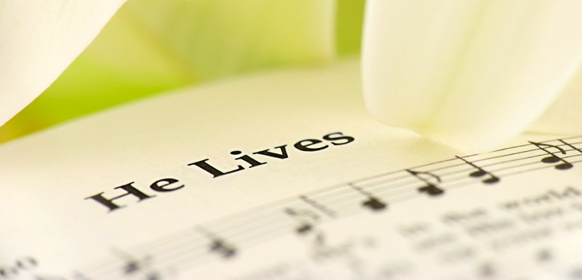Extreme close up of a hymnal and easter lily petals. Very shallow depth of field with focus on only part of the words, "He Lives".