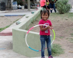 Young girl having fune with hoola-hoop in the park