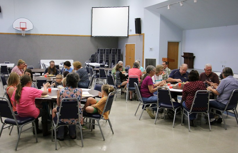 Grandparentsm kids and mentors eating in at tables in the gym