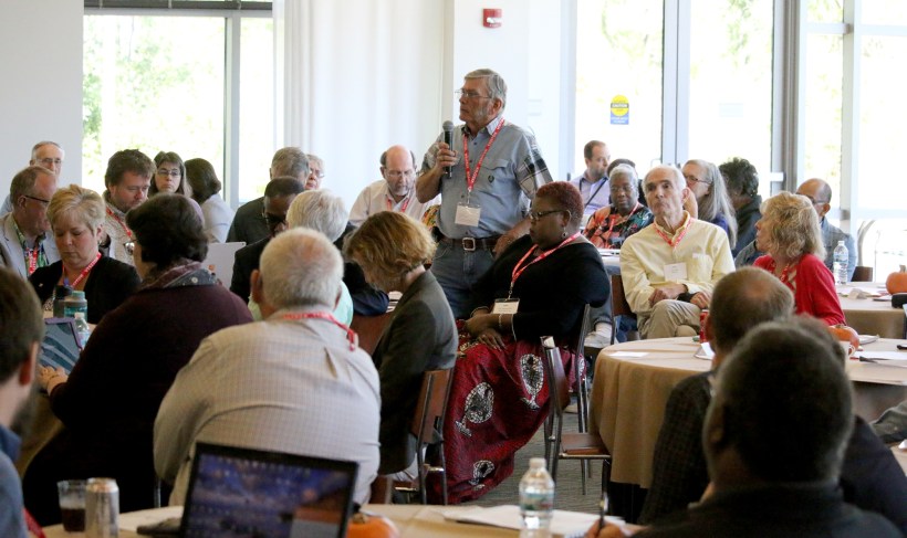 Delegate stands to speak among seated delegates.
