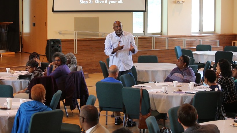 Rev. Dr. Joseph Daniels, Jr. speaks to partipanst seated at tables