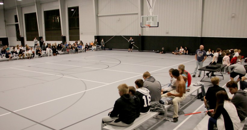 Clergy devotion, full view of gym, students sitting on bleachers