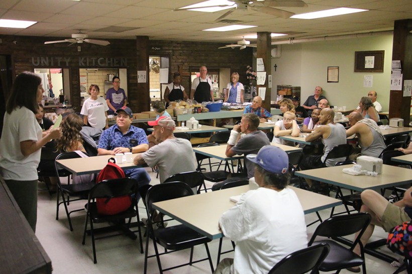 Rev. Ashley Steele speaks before meal,to those seated at the tables