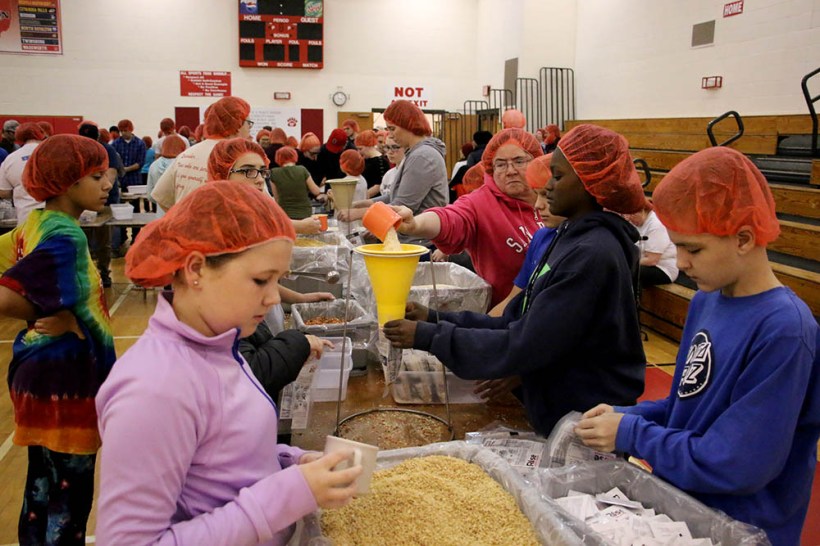 Youth in production line packing meals